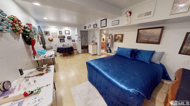 bedroom with beam ceiling and light wood-type flooring