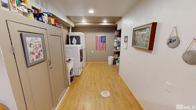 laundry room with separate washer and dryer and light hardwood / wood-style flooring