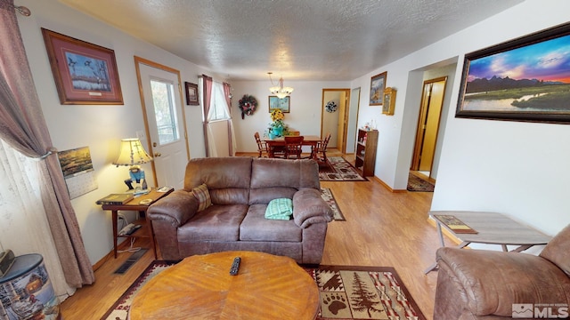 living room featuring an inviting chandelier, a textured ceiling, and light hardwood / wood-style floors