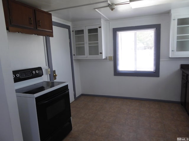 kitchen with white range with electric stovetop, dark tile floors, dark brown cabinetry, and white cabinets