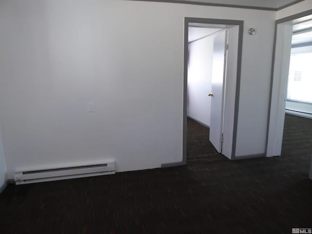 empty room featuring baseboard heating and dark wood-type flooring