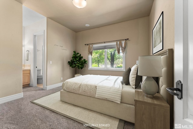 bedroom with ensuite bathroom and light carpet