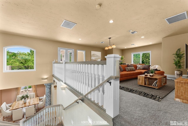 living room featuring a chandelier, a textured ceiling, and dark colored carpet