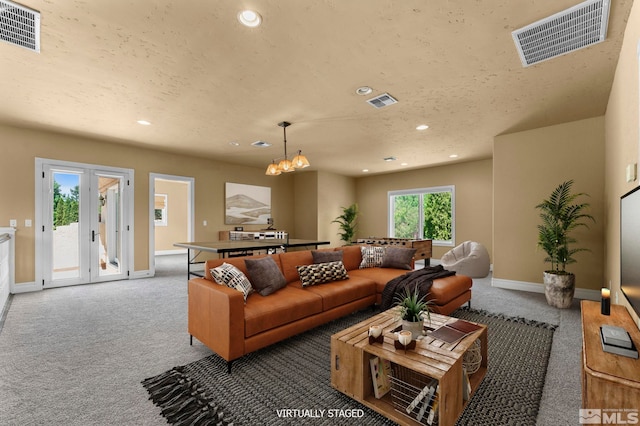 living room featuring a textured ceiling, dark carpet, and a chandelier