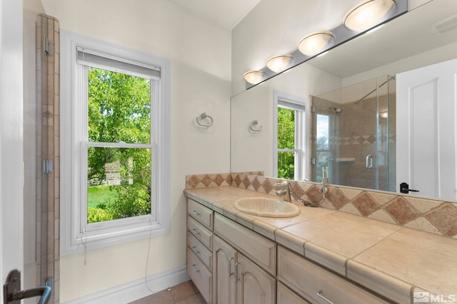 bathroom featuring a shower with door, vanity with extensive cabinet space, tile floors, and a wealth of natural light