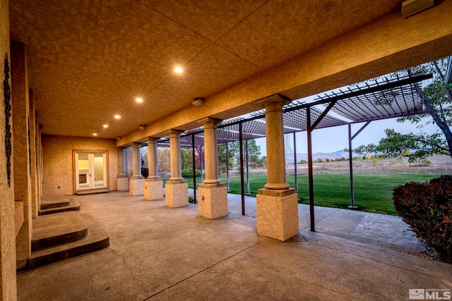 patio terrace at dusk featuring a pergola and a lawn