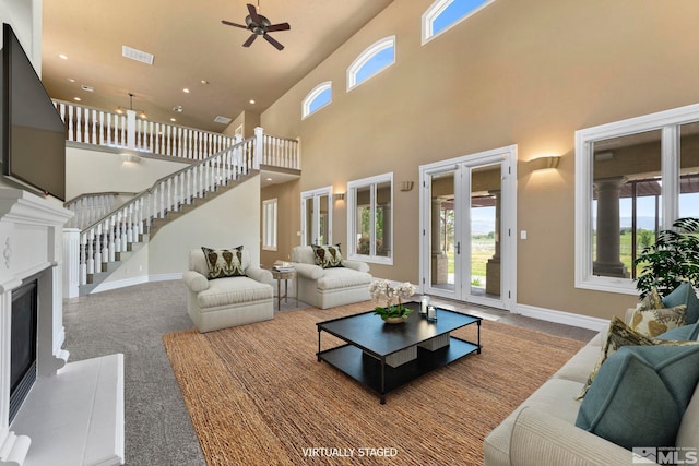 carpeted living room featuring ceiling fan, a towering ceiling, and french doors