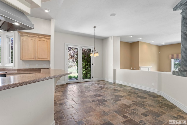 kitchen featuring decorative light fixtures, a notable chandelier, light brown cabinetry, wall chimney exhaust hood, and dark tile floors