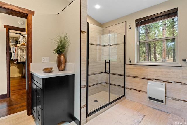 bathroom with vaulted ceiling, walk in shower, vanity, and hardwood / wood-style flooring