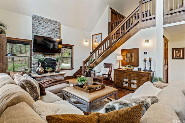 living room with a towering ceiling, hardwood / wood-style floors, and a fireplace