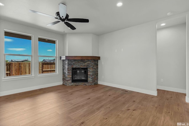 unfurnished living room with a fireplace, light wood-type flooring, and ceiling fan