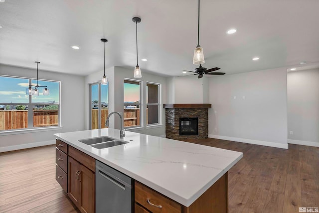 kitchen with a center island with sink, decorative light fixtures, sink, and stainless steel dishwasher