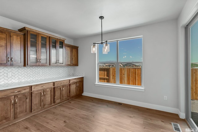 kitchen featuring hanging light fixtures, tasteful backsplash, light hardwood / wood-style flooring, and an inviting chandelier