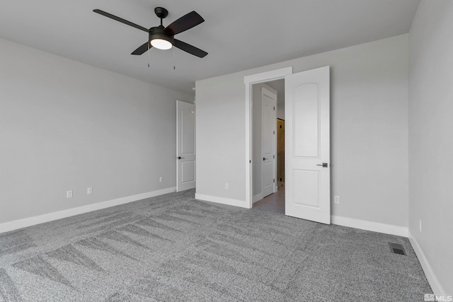 spare room featuring dark colored carpet and ceiling fan