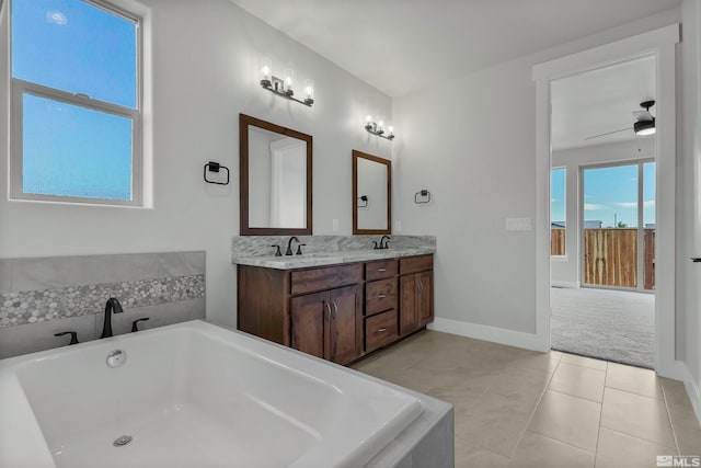 bathroom featuring ceiling fan, double sink vanity, a relaxing tiled bath, and tile floors