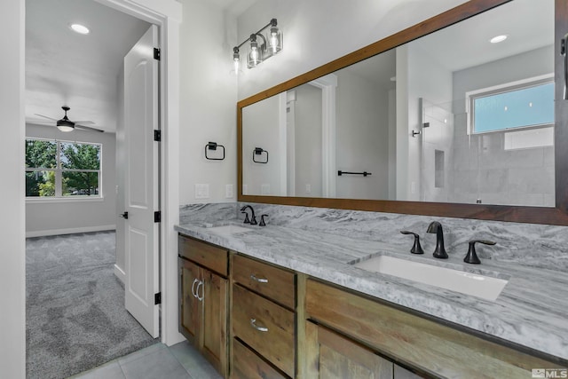 bathroom with a tile shower, ceiling fan, dual sinks, tile flooring, and large vanity