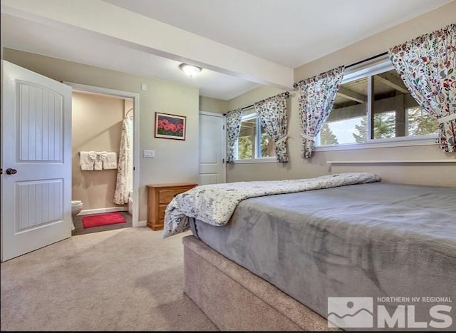 bedroom featuring ensuite bath, beam ceiling, and carpet floors