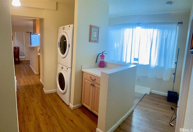 washroom featuring stacked washer and clothes dryer and light wood-type flooring