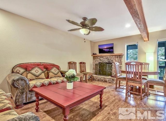 interior space with ceiling fan, a fireplace, beam ceiling, and light hardwood / wood-style flooring