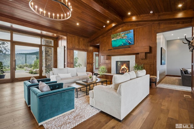 living room with a notable chandelier, wooden walls, wooden ceiling, hardwood / wood-style flooring, and a high end fireplace