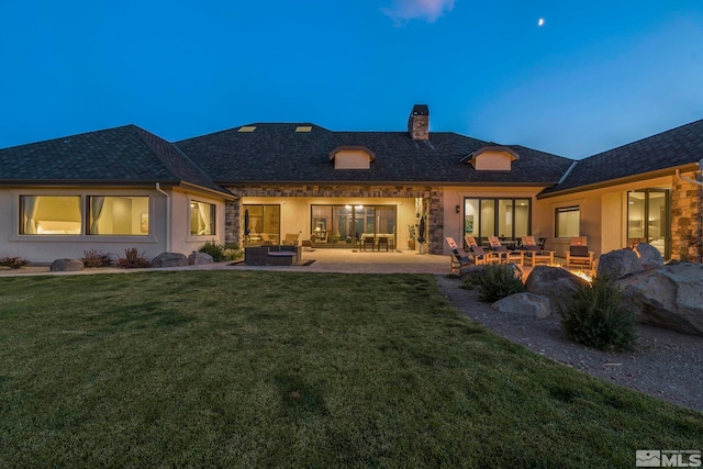 back house at dusk with a patio area, an outdoor hangout area, and a yard