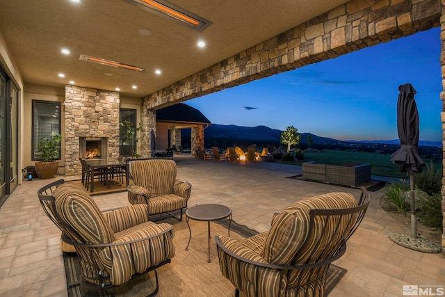 patio terrace at dusk with an outdoor living space with a fireplace