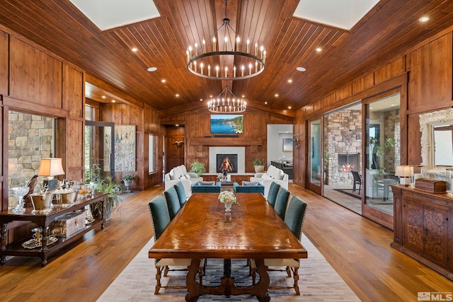 dining room featuring a stone fireplace, wood-type flooring, wood walls, and wood ceiling