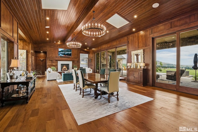 dining area featuring wood walls, wood ceiling, hardwood / wood-style floors, and a large fireplace