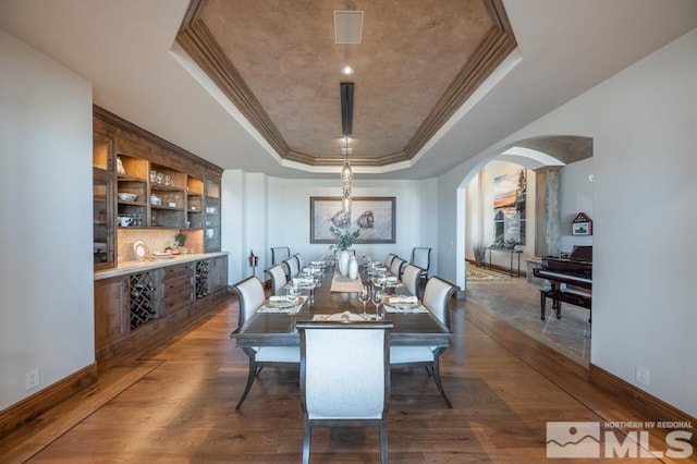 dining space featuring crown molding, dark hardwood / wood-style floors, and a raised ceiling