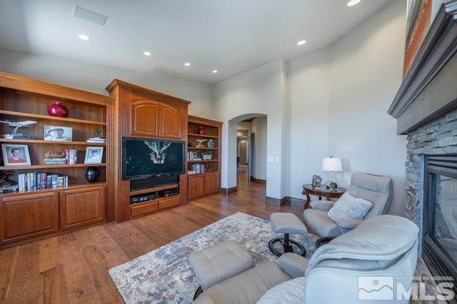 living room with high vaulted ceiling, light wood-type flooring, and a fireplace