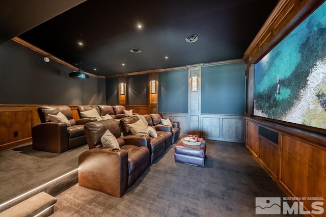 carpeted home theater room featuring crown molding