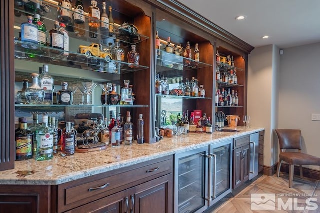 bar featuring light stone countertops, light parquet flooring, beverage cooler, dark brown cabinets, and sink