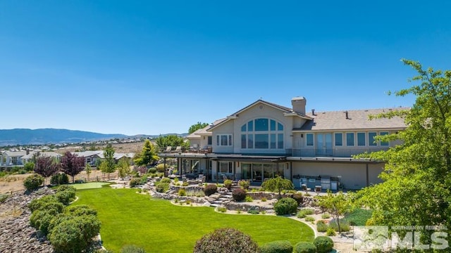 rear view of property featuring a mountain view and a yard