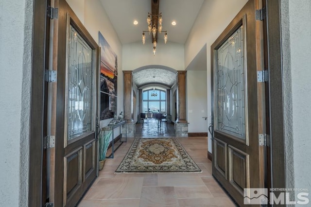 hall with a chandelier, vaulted ceiling, and light tile floors