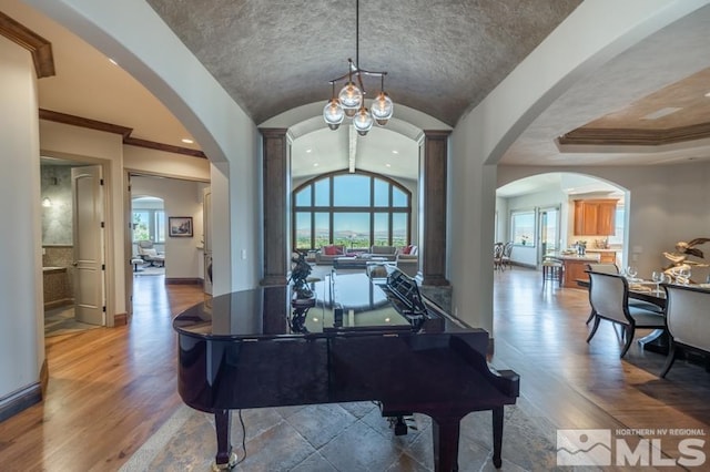 misc room with an inviting chandelier, wood-type flooring, a tray ceiling, and lofted ceiling