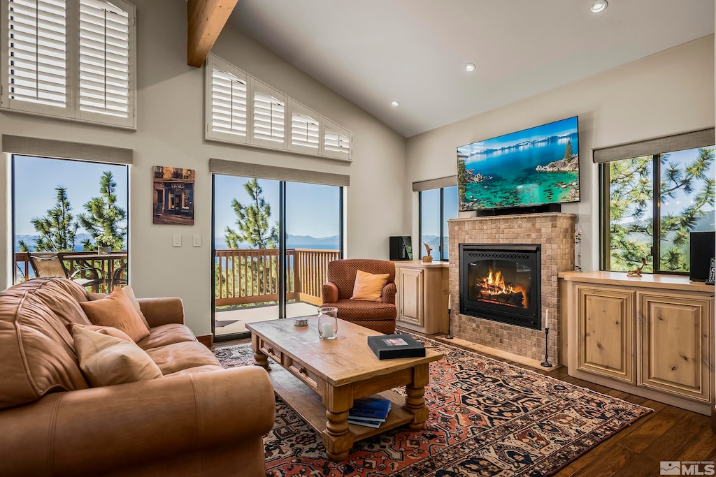 living room featuring high vaulted ceiling, dark hardwood / wood-style floors, a tile fireplace, and beamed ceiling