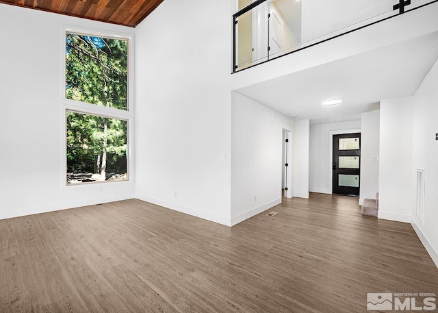 unfurnished living room with high vaulted ceiling, dark wood-type flooring, and wooden ceiling