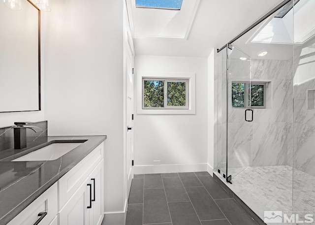 bathroom featuring tile floors, a shower with door, a skylight, and vanity