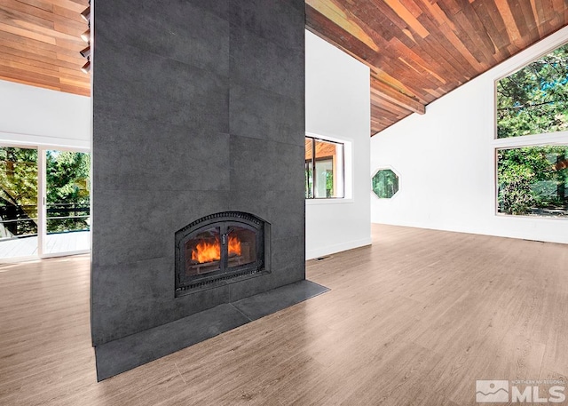 unfurnished living room with a healthy amount of sunlight, hardwood / wood-style floors, a large fireplace, and wood ceiling