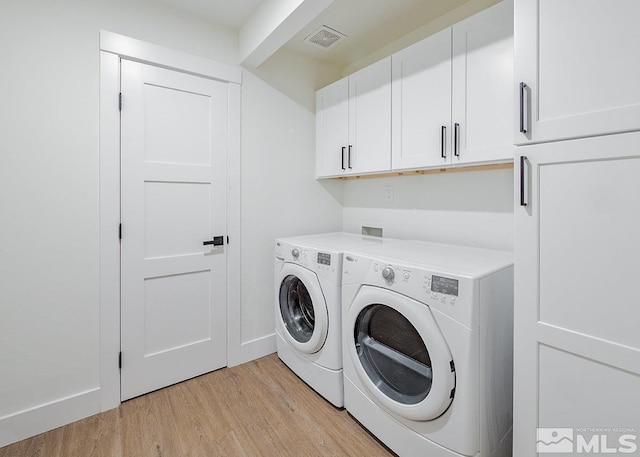 laundry room featuring hookup for a washing machine, light hardwood / wood-style floors, washer and clothes dryer, and cabinets