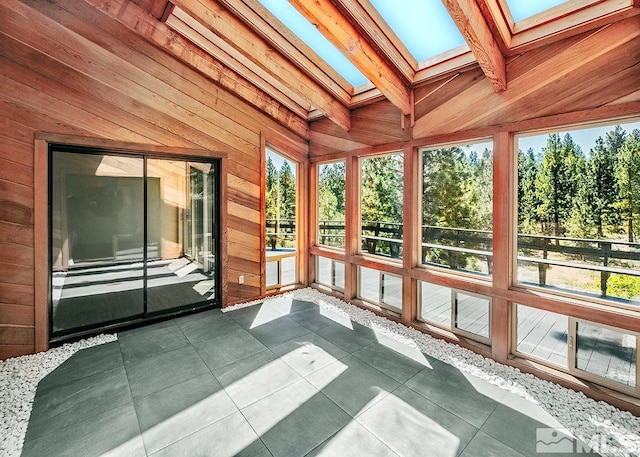 unfurnished sunroom featuring vaulted ceiling with skylight