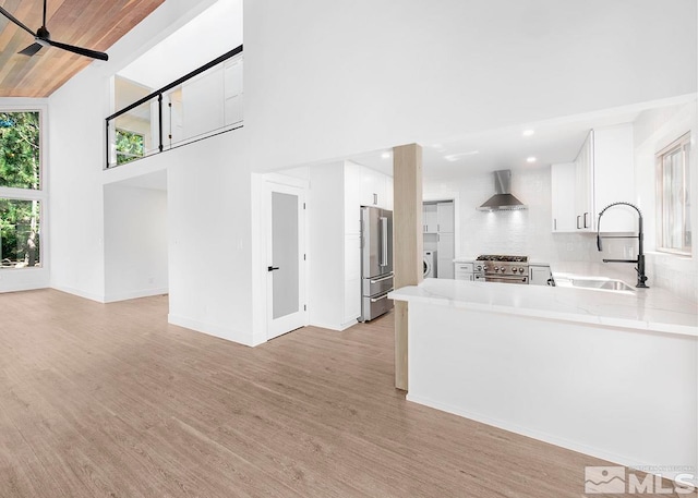 kitchen featuring white cabinets, sink, wall chimney exhaust hood, and light wood-type flooring