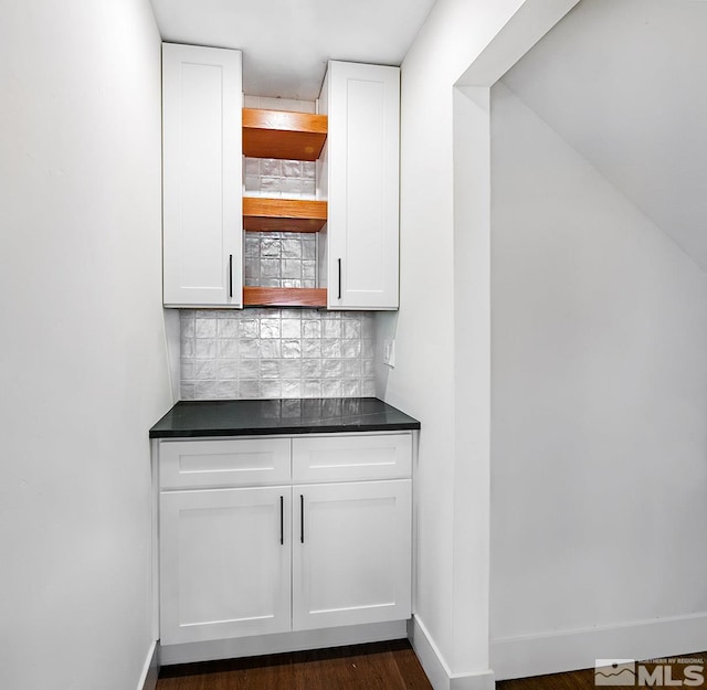 bar featuring dark hardwood / wood-style floors, backsplash, and white cabinetry