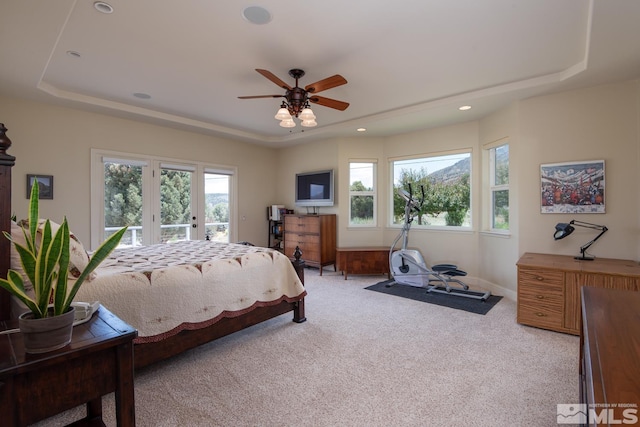 bedroom featuring ceiling fan, a tray ceiling, light carpet, and access to exterior