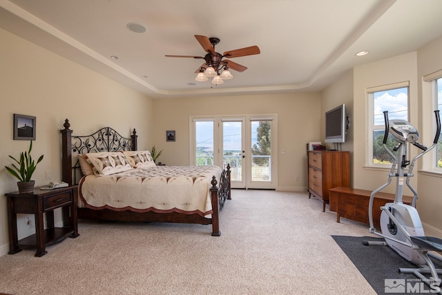 carpeted bedroom featuring ceiling fan, a tray ceiling, access to outside, and french doors