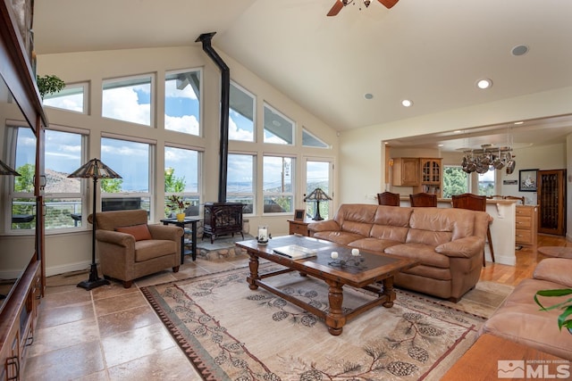 tiled living room featuring ceiling fan, a wood stove, and high vaulted ceiling