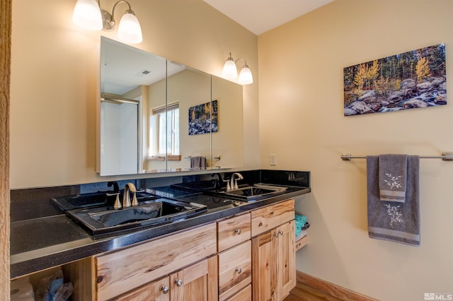 bathroom with double sink, large vanity, and hardwood / wood-style flooring