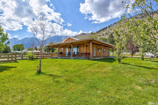 back of property featuring a mountain view and a lawn