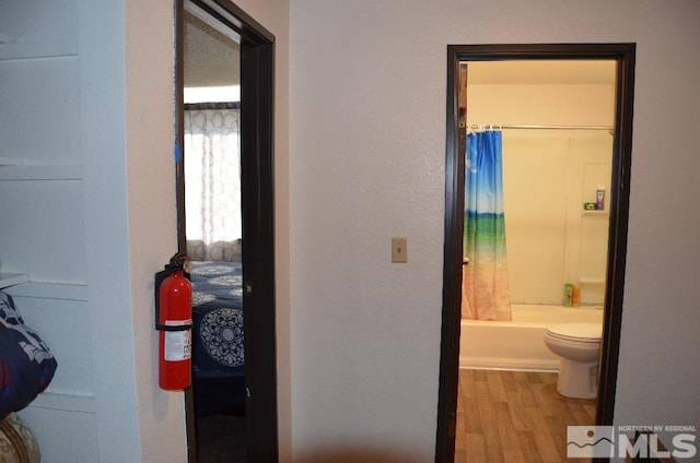 bathroom with shower / bath combination with curtain, toilet, and hardwood / wood-style floors