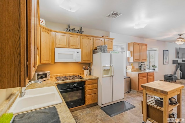 kitchen with light tile floors, light brown cabinetry, ceiling fan, white appliances, and sink